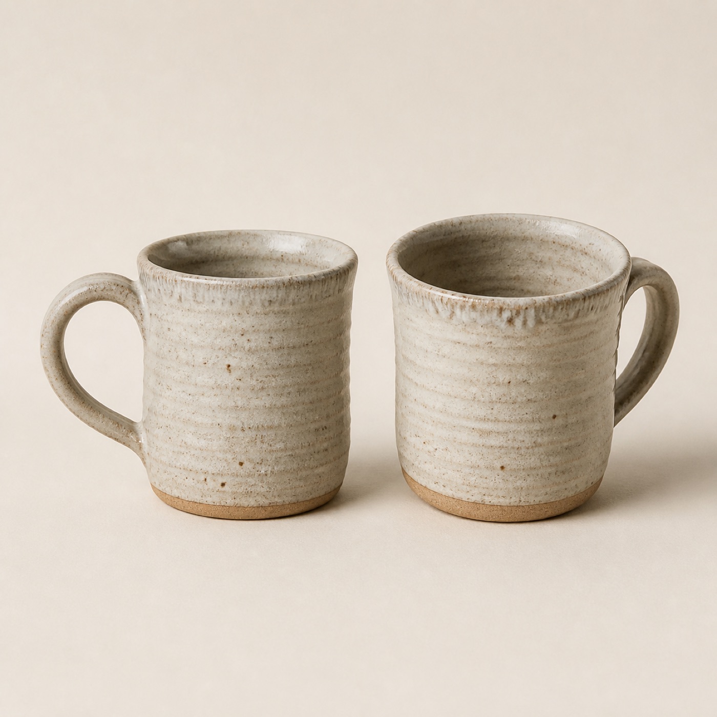 Two pale clay stoneware mugs with hand-pulled handles