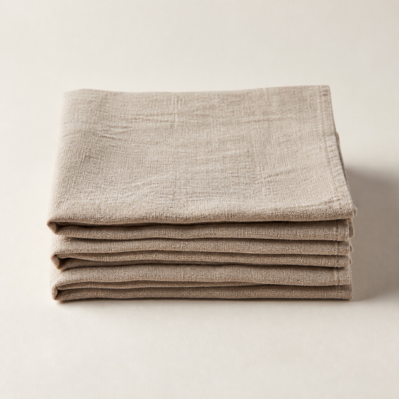 A stack of four washed oatmeal linen napkins
