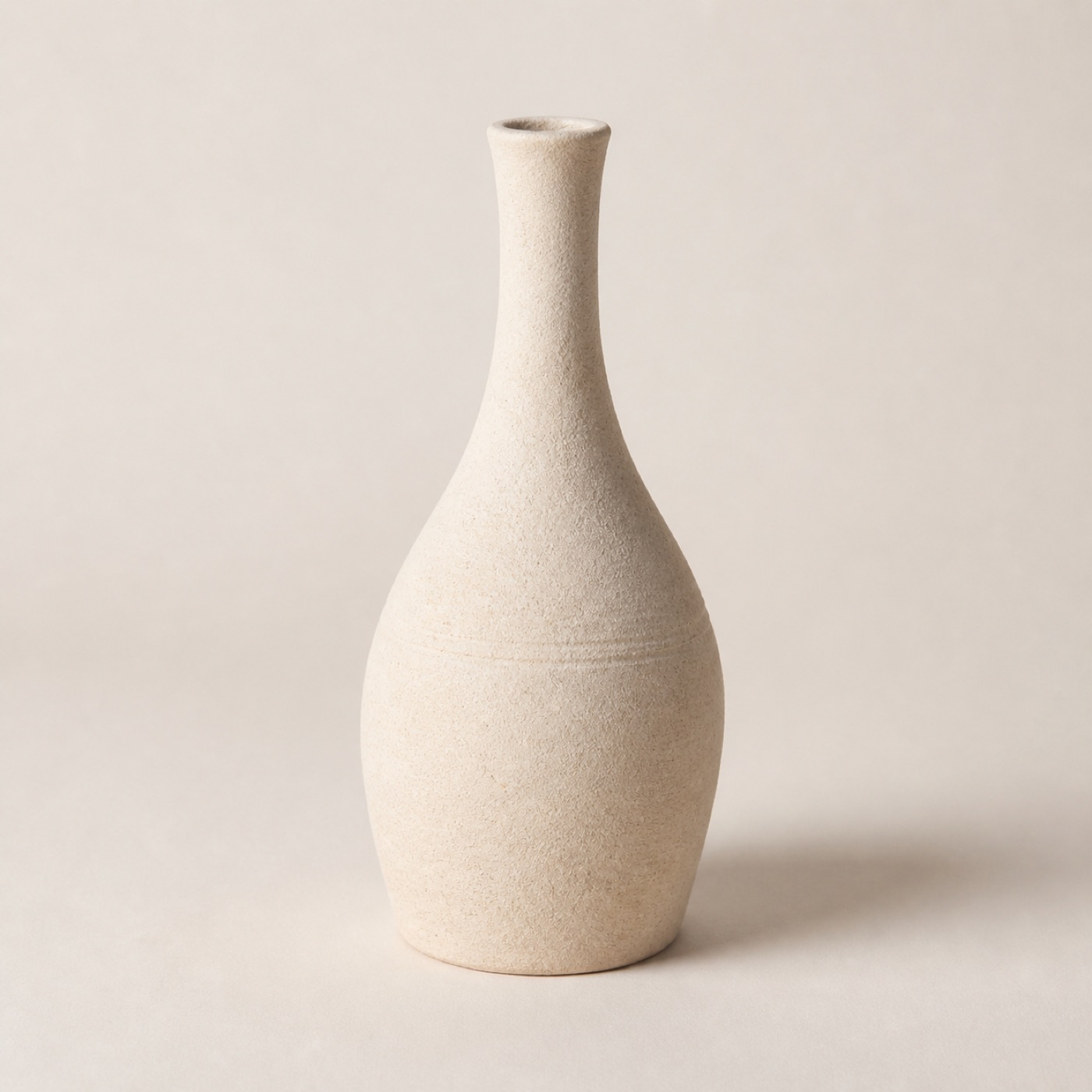 A tall narrow-necked bone-white stoneware bud vase, unglazed
